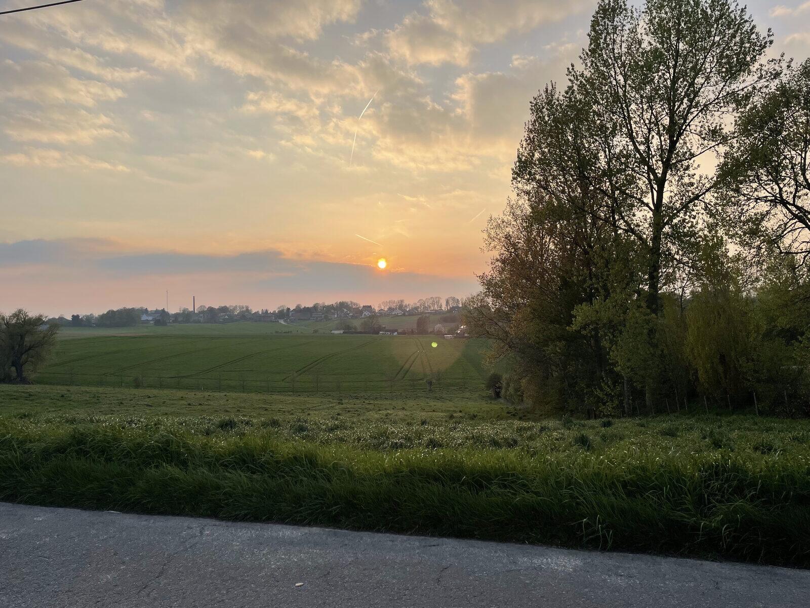 Zonsondergang boven de velden aan de rand van een dorp in het Waasland